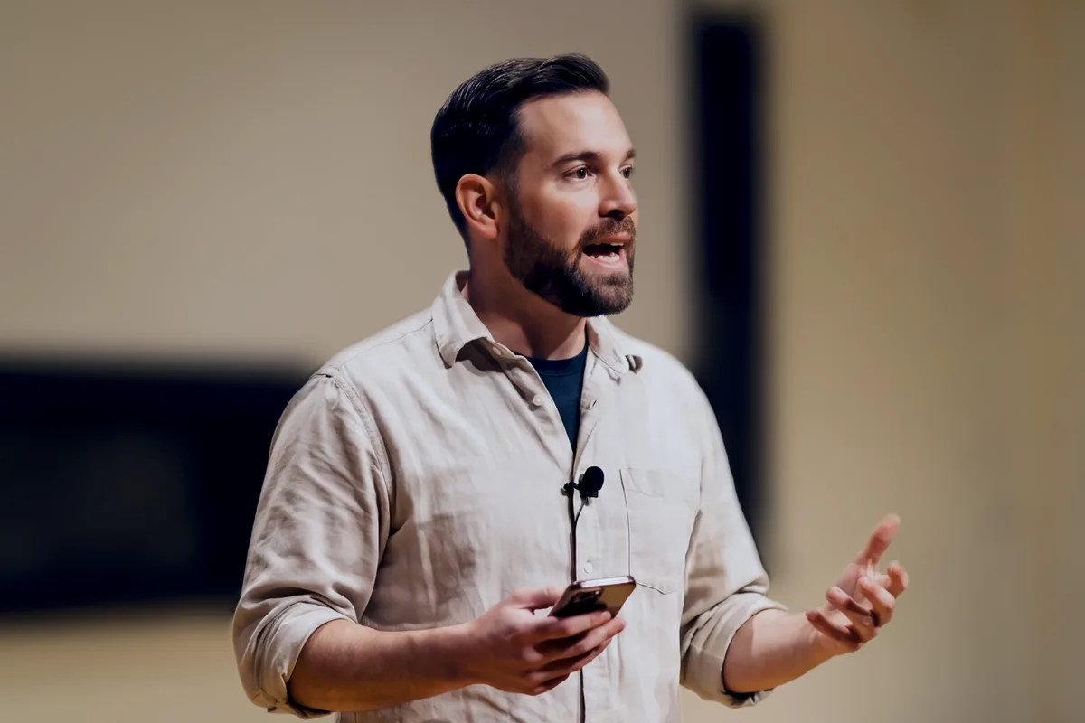 Matt Starfield speaking, a phone in one hand, gesturing with the other